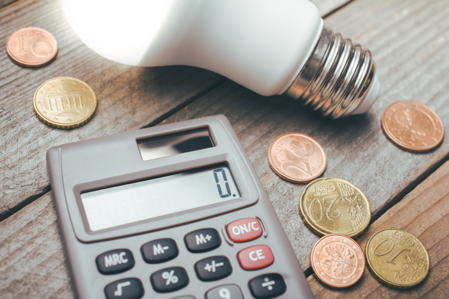 una bombilla encendida con dinero y una calculadora